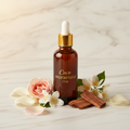 Coco Mademoiselle type fragrance oil amber bottle with gold dropper, rose petals and jasmine on white marble