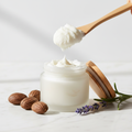 Whipped Shea Butter in a glass jar on white marble surface