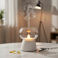 Electric glass oil burner diffuser with warm glow on white marble surface
